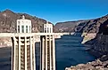 Detailed view of the Hoover Dam intake towers standing above the Colorado River, showing water levels and surrounding rocky desert terrain