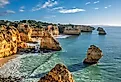 View of Praia da Marinha beach in Algarve, Portugal, with ocean cliffs, sea stacks and scenic coastline. Credit: Dmitry Rukhlenko / Shutterstock