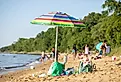 A beach umbrella stands in the sand at Matapeake Clubhouse and Beach on Kent Island, Maryland. Image credit Nicole Glass Photography via Shutterstock. 