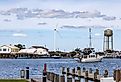 A view of the port in Crisfield with boats, a water tower and a wind turbine. Image credit: Alexanderstock23 via Shutterstock.