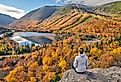 Woman hiking at Artist's Bluff in autumn, with a view of Echo Lake, New Hampshire.