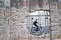 A man ride a bicycle pass the hole in section of ruined Berlin Wall in Germany.