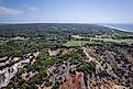 Aerial of scenic cliffs and lighthouse at Gay Head in Martha's Vineyard, with lush greenery and ocean views.