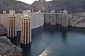 Detailed view of the Hoover Dam intake towers standing above the Colorado River, showing water levels and surrounding rocky desert terrain