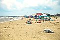 People enjoying a a busy summer beach day in Dauphin Island, Alabama. Image credit: HarrisonJeffs / Shutterstock.com