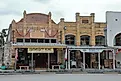 The Empresario Restautant and Hanging Tree Antiques buildings in the downtown historic courthouse square - Goliad, Texas, via JustPixs / Shutterstock.com