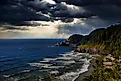 Light rays filter through storm clouds and illuminate the Heceta Head Lighthouse on the Oregon Coast.
