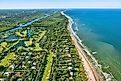 aerial view looking north, of Jupiter and Hobe Sound, Florida, along the Atlantic Ocean coast, lined by the beach and dotted by luxury homes golf courses
