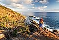 A young woman admires a coastal view at sunrise near Coffs Harbour, Australia.
