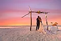 Bride and groom on the beach under wedding arch with cake.