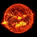 Solar flare on the left side of the sun and an eruption of solar material shooting through the sun’s atmosphere, called a prominence eruption