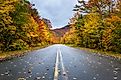 Deserted Straight Mountain Road on a Rainy Autumn Day. Some Fallen Leaves are on the Wet Asphalt. Beautiful Fall Colors. Adirondacks, Upstate New York