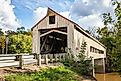 The Mechanicsville Covered Bridge crosses Grand River during the Autumn leaf color change in Ashtabula County, Ohio.