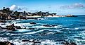 Waves splash on the rocky coast along the Monterey Bay in Pacific Grove, California on a windy winter day.