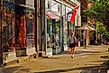 A young woman walks past independent stores and boutiques on a sunny day in Cold Spring, New York