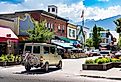A camperized van with mountain bikes drives down the Main Street, with Selkirk Mountains in Revelstoke, British Columbia. Image credit Ramon Cliff via Shutterstock 