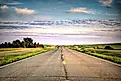 a long country highway rural highway road in North Dakota at sunset with a colorful sky. Editorial credit: adobe stock