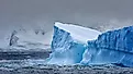 Massive Iceberg floating in the Southern Ocean in Antarctica with snow covered mountains in the background