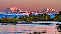 Sunrise on Mount Foraker and Mount Hunter across the Susitna River with fall foliage.