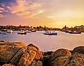 Rocky shoreline surrounds fishing boats in the Corea Harbor at sunset in Maine. 