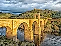 Ancient Roman stone arch bridge connecting hills over Tagus River in Alcántara, Spain.