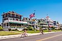 People bike and walk in front of traditional villas in Cape May, New Jersey.