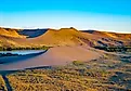 Vibrant golden sunset glow illuminates the towering sand dunes at Bruneau Dunes State Park. Credit: Photo Spirit/ Shutterstock.com