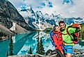 A couple taking a photo in Moraine Lake, Alberta.