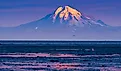 Mount Redoubt is illuminated by the rising sun as it stands tall over the calm waters of Cook Inlet.