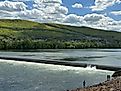 People on the bank fishing by the dam at the West Branch of the Susquehanna River in Williamsport, Pennsylvania.