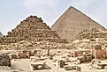Pyramids of Giza complex in Cairo, Egypt, with Menkaure, Khafre, and Khufu pyramids under clear desert sky.