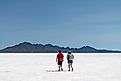 Two people walking on the white salt pan of the Bonneville Salt Flats a remnant of the Pleistocene Lake Bonneville. 