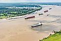 A variety of different cargo ships sailing along the Mississippi River near New Orleans