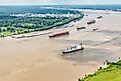 A variety of different cargo ships sailing along the Mississippi River near New Orleans