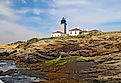 Editorial Photo Credit:Stephen B. Goodwin via Shutterstock. The Beavertail Light lighthouse near Jamestown on Conanicut Island, Rhode Island, viewed from the rocky coast with a bright blue sky and white clouds