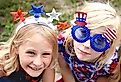 Two Patriotic little kids are sitting at a Fourth of July parade in a small town in America.