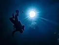 Underwater POV of sunburst with scuba diver in a blue hole, similar to what it would look like in the Green Banana. 