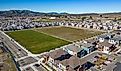 Aerial photos over apartments and houses in Dublin, California with a green field and solar panels