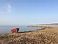 A lonely red metal boat on a a rocky shoreline with blues skies. Baker Lake, Nunavut