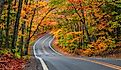 A tunnel of vibrant autumn trees lines the scenic byway M41 on the Keweenaw Peninsula in Michigan's Upper Peninsula.