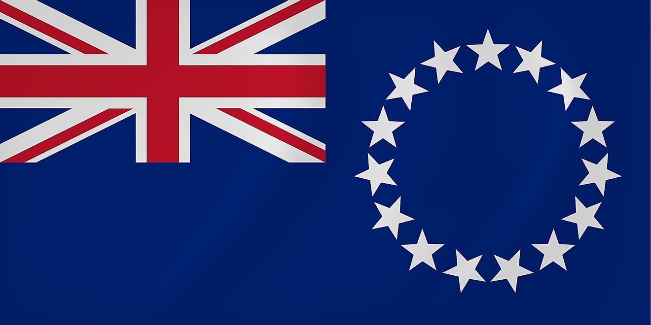 The National Flag of Cook Islands features a blue background with the Union Jack (flag of the UK) in the upper hoist-side quadrant and a large circle of 15 white five-pointed stars centered in the outer half of the flag. 