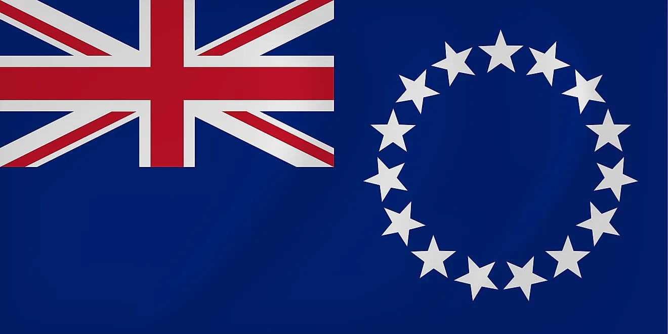 The National Flag of Cook Islands features a blue background with the Union Jack (flag of the UK) in the upper hoist-side quadrant and a large circle of 15 white five-pointed stars centered in the outer half of the flag. 