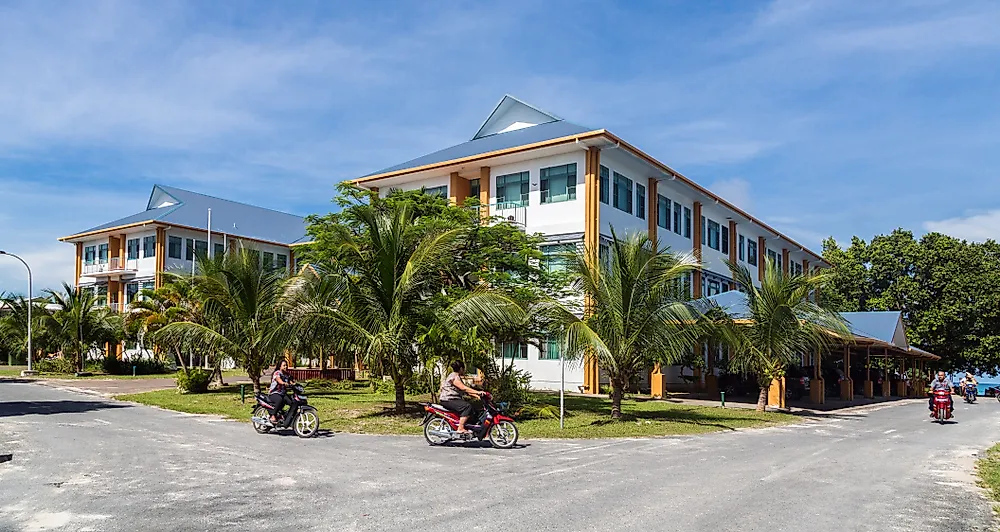 Tuvaluans ride their bikes bask the Tuvalu government building. Editorial credit: maloff / Shutterstock.com.