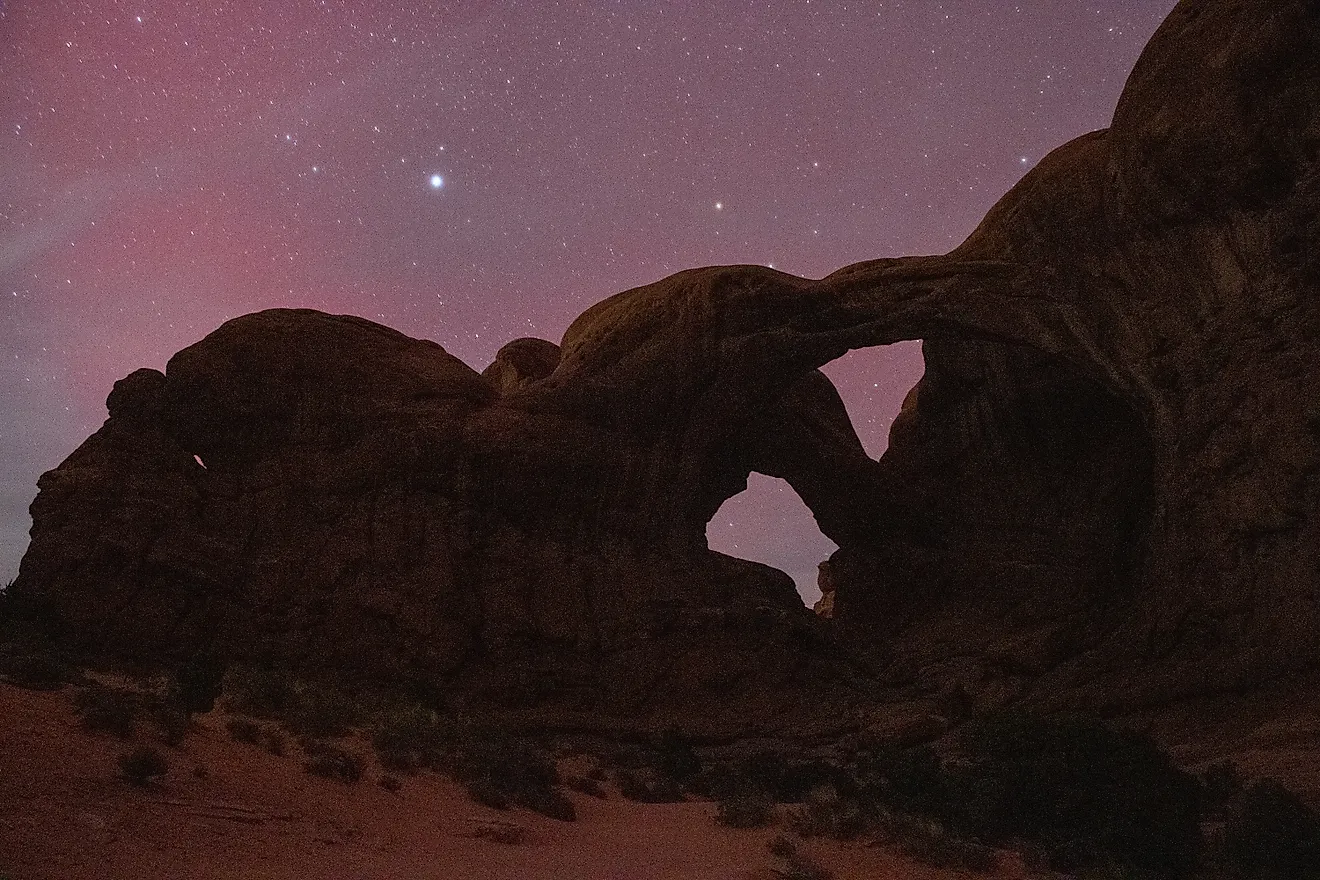 Rare aurora borealis dancing above Double Arch in Arches National Park, Utah - an extraordinary celestial event over iconic southwestern landscape