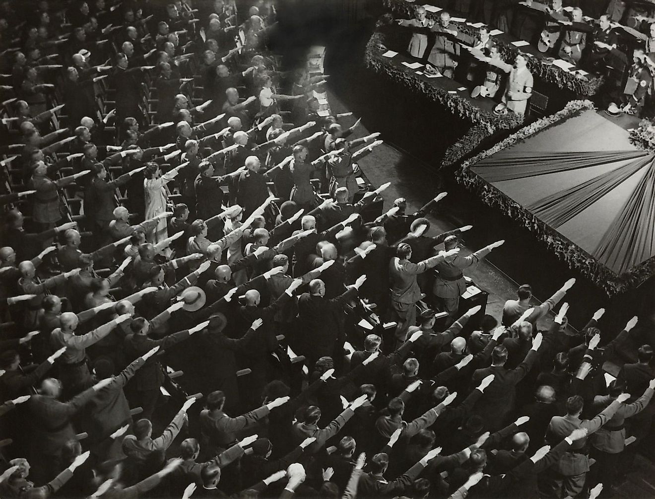 Attendees give Hitler the Nazi salute during the nation anthem, Oct. 9, 1935. They were meeting at the Kroll Opera in Berlin, to organize the Winter Relief festive to help finance charitable work. Image credit: Everett Collection/Shutterstock.com
