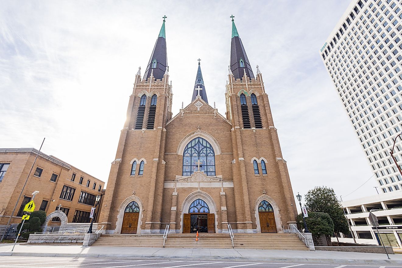 Exterior of Holy Family Cathedral in Tulsa, featuring Romanesque Revival architecture with arched windows, twin bell towers, and a detailed brick facade