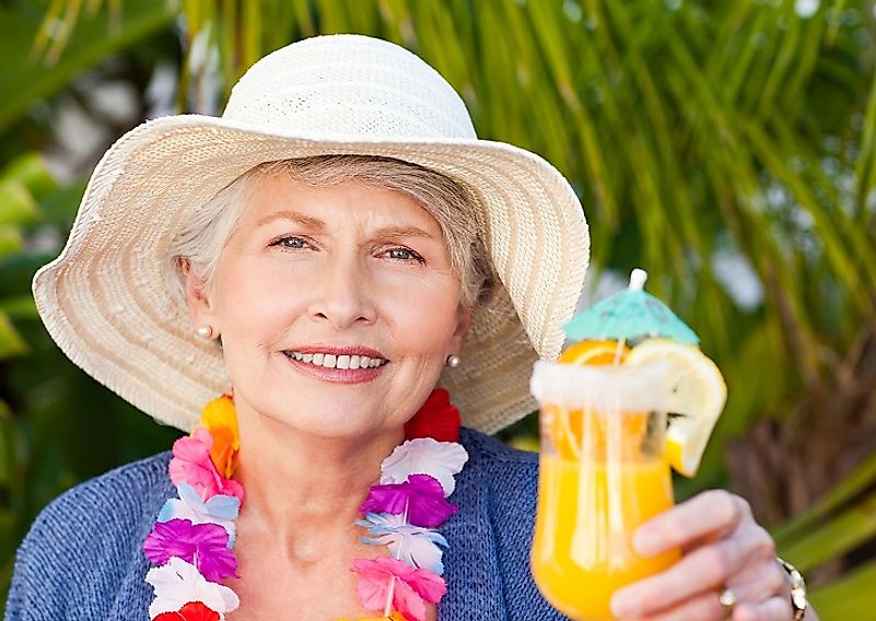 A female retiree enjoys a margarita at the beach in Mexico.