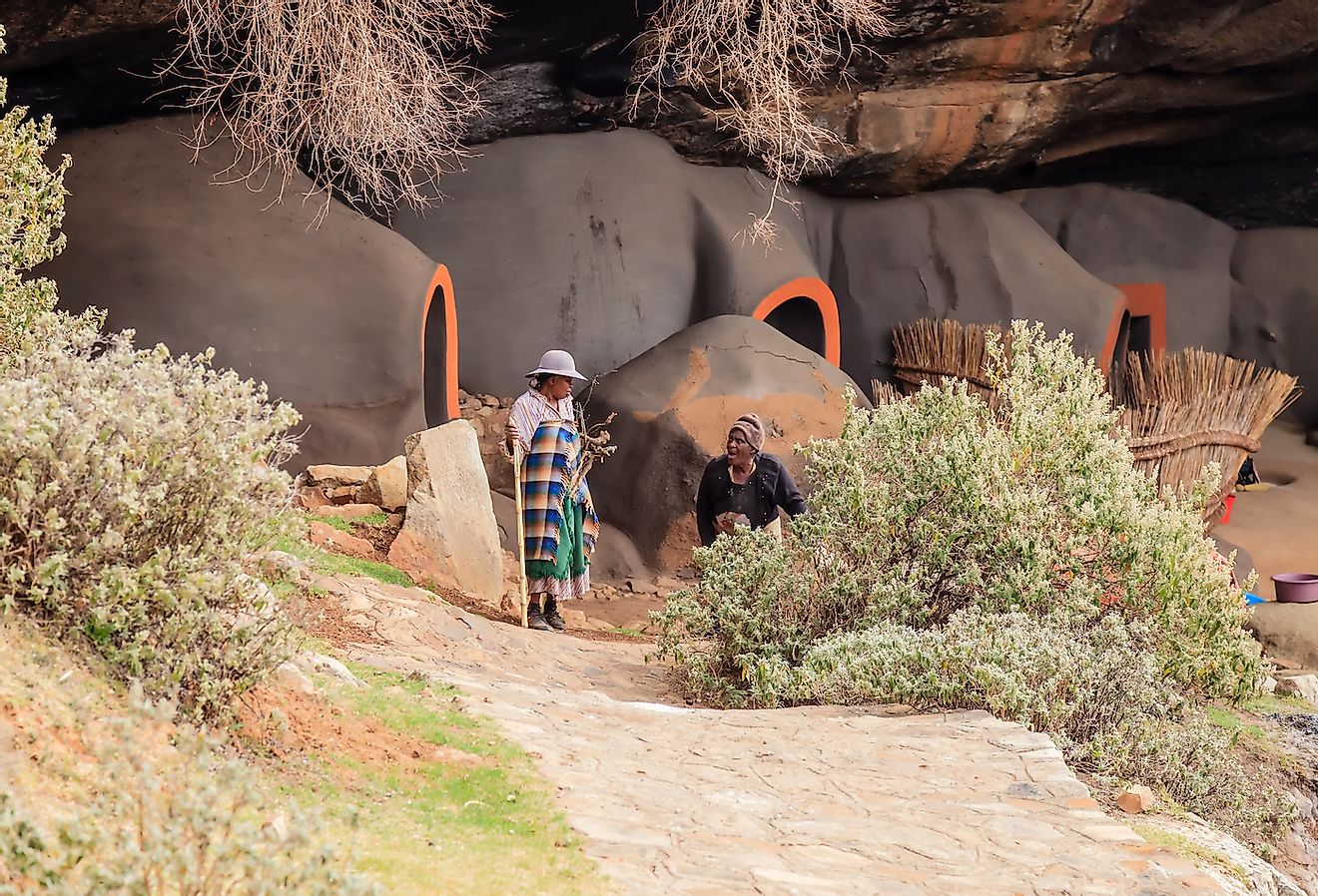 Two indigenous women in front of cave dwellings made out of mud in the district of Berea, Lesotho. Image credit: Chr. Offenberg/Shutterstock.com