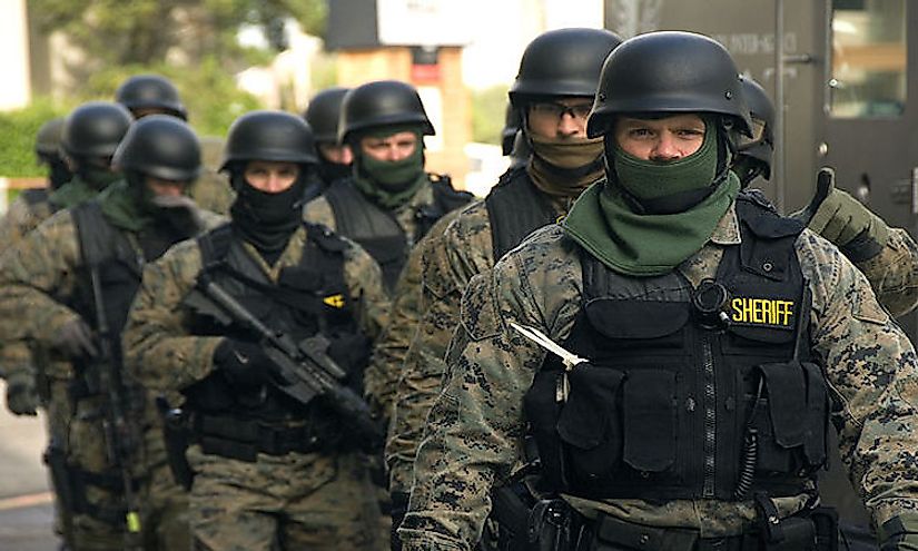 SWAT team members, some armed with assault rifles, prepare for an exercise.