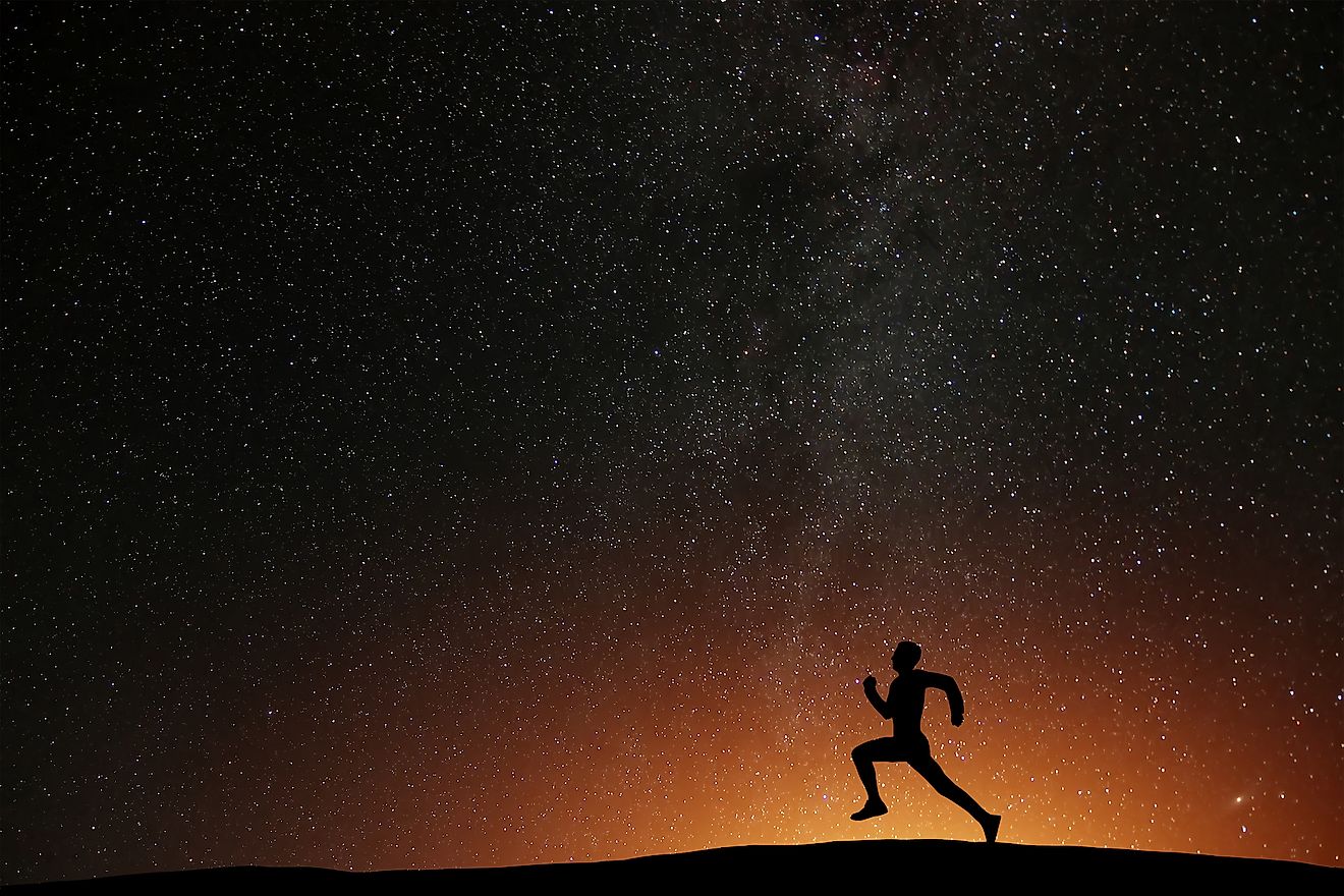 Runner athlete running on the hill with beautiful starry night background.